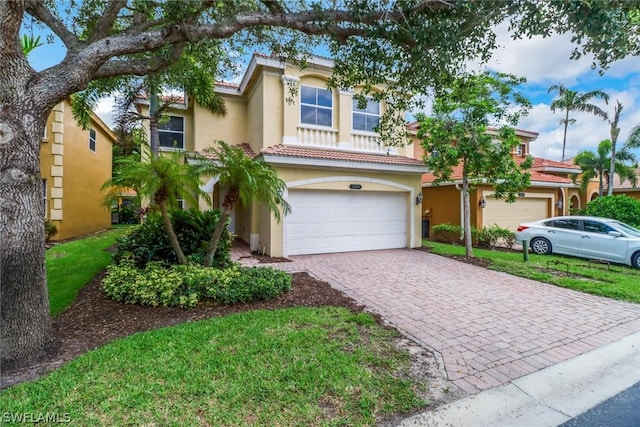 mediterranean / spanish home with decorative driveway, a tiled roof, an attached garage, and stucco siding