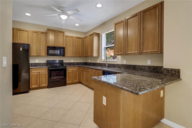 kitchen with light tile patterned floors, a peninsula, a sink, dark stone counters, and black appliances