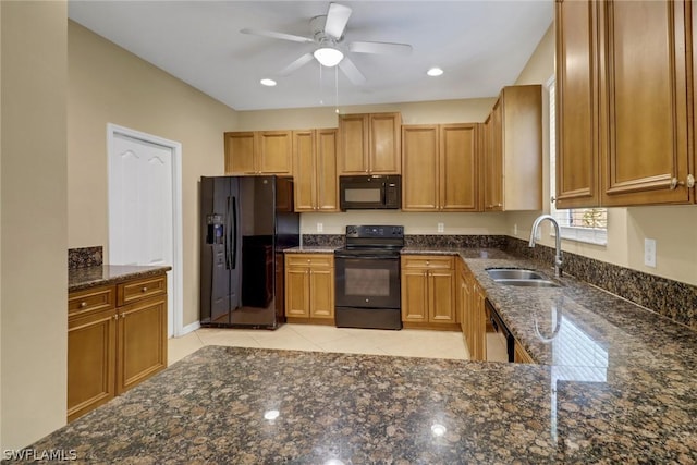 kitchen featuring dark stone counters, a ceiling fan, black appliances, a sink, and light tile patterned flooring