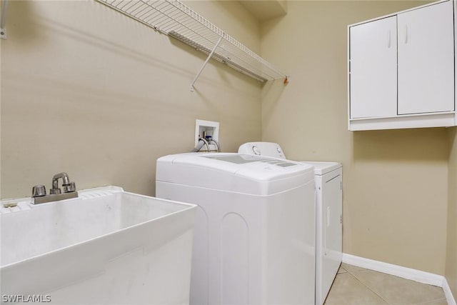 clothes washing area featuring washer and clothes dryer, light tile patterned floors, cabinet space, a sink, and baseboards