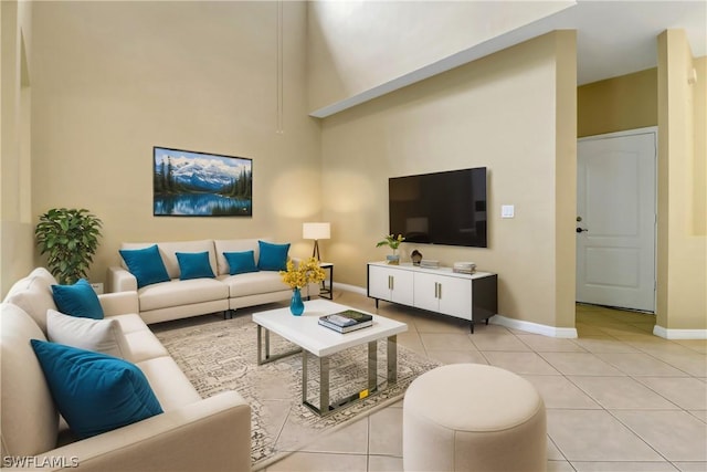 living area with a high ceiling, baseboards, and light tile patterned flooring