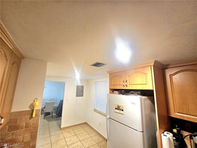 kitchen featuring electric panel, white refrigerator, light tile patterned floors, and light brown cabinets