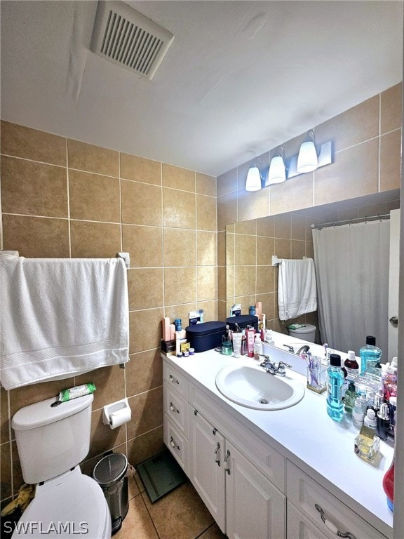 bathroom with vanity, toilet, tile patterned floors, and tile walls