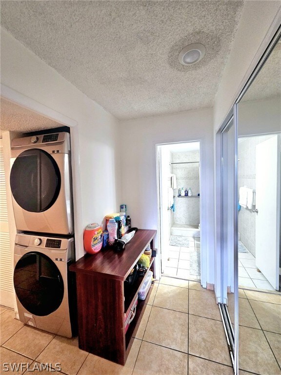 washroom featuring stacked washer / dryer, a textured ceiling, and light tile patterned floors