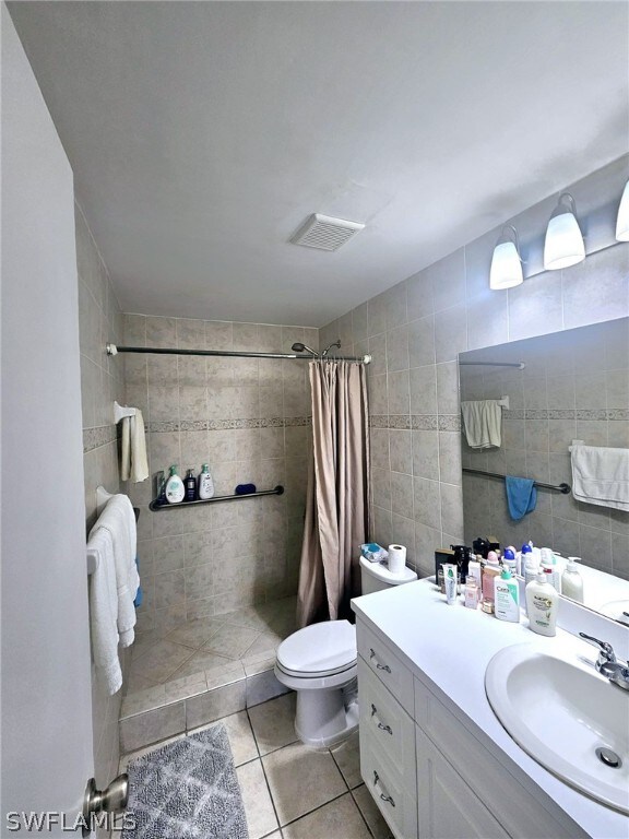 bathroom featuring vanity, toilet, tile patterned floors, and tile walls