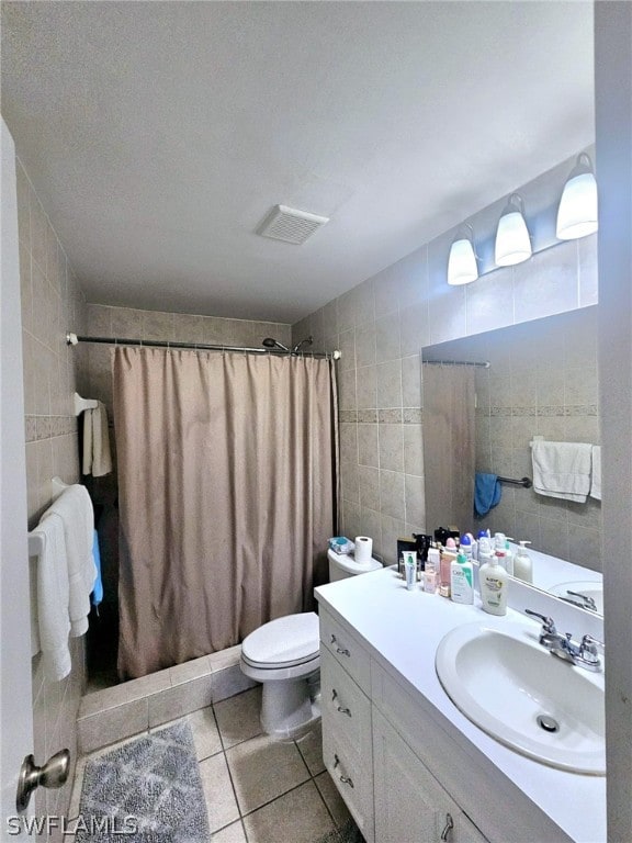 bathroom with vanity, toilet, tile patterned flooring, and tile walls