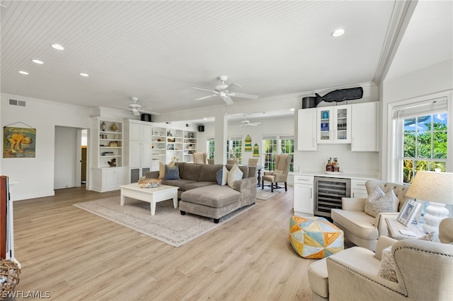 living room with wine cooler, crown molding, and light wood-type flooring