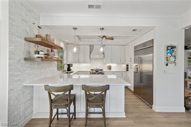 kitchen with white cabinetry, sink, stainless steel appliances, a kitchen breakfast bar, and kitchen peninsula