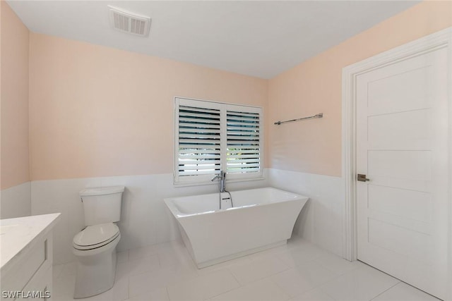 bathroom with a bathing tub, vanity, toilet, and tile patterned floors