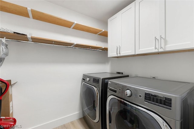 laundry area with washing machine and clothes dryer, cabinets, and light hardwood / wood-style floors