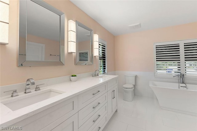 bathroom featuring a tub, tile patterned flooring, toilet, vanity, and tile walls