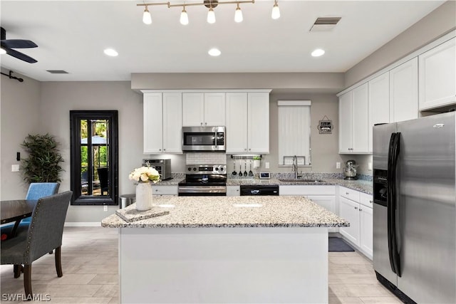 kitchen featuring stainless steel appliances, a kitchen island, white cabinetry, and sink