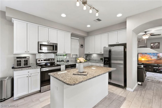 kitchen with appliances with stainless steel finishes, a center island, white cabinetry, and ceiling fan