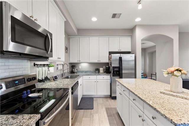 kitchen with light stone countertops, white cabinetry, sink, and appliances with stainless steel finishes