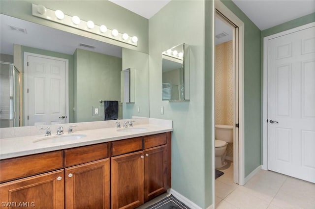 bathroom with tile patterned floors, a shower with door, vanity, and toilet