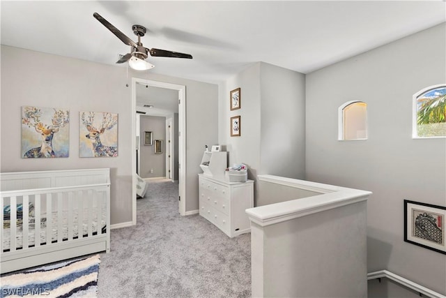 bedroom with ceiling fan, a nursery area, and light carpet