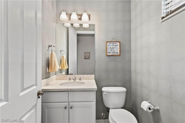 bathroom with vanity, tile walls, and toilet