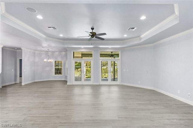 interior space with french doors, ceiling fan with notable chandelier, a raised ceiling, ornamental molding, and light wood-type flooring