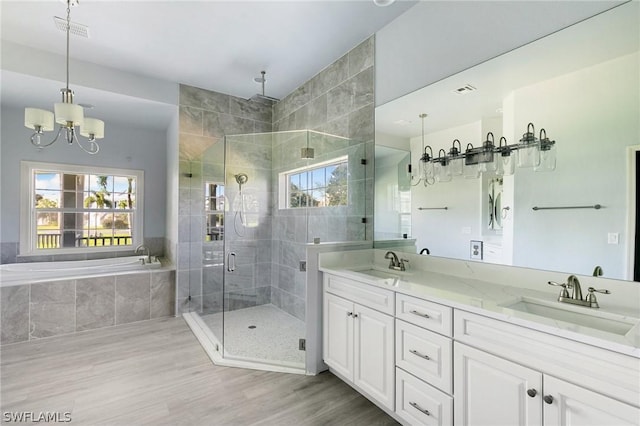 bathroom with hardwood / wood-style flooring, vanity, independent shower and bath, and an inviting chandelier