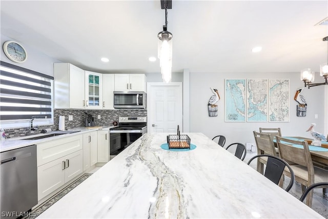 kitchen with white cabinetry, appliances with stainless steel finishes, a breakfast bar area, and hanging light fixtures