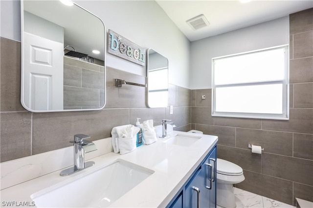 bathroom with vanity, tile walls, and toilet