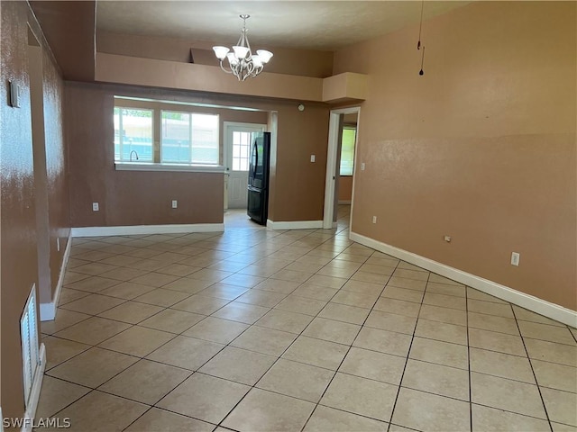 unfurnished room featuring light tile patterned floors and an inviting chandelier