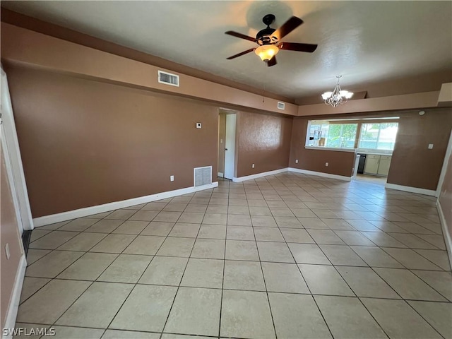 tiled spare room featuring ceiling fan with notable chandelier