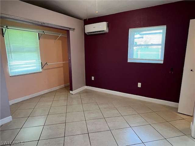 spare room featuring an AC wall unit and light tile patterned flooring