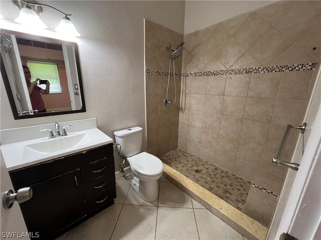 bathroom featuring tiled shower, tile patterned flooring, vanity, and toilet