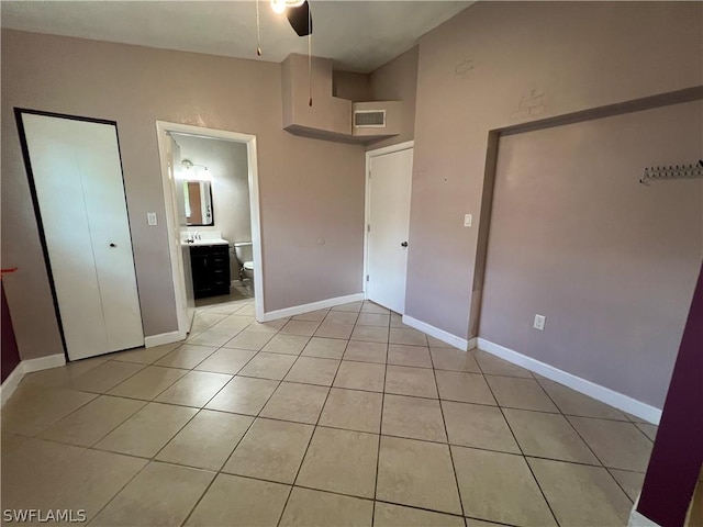 unfurnished bedroom featuring light tile patterned floors, a closet, ceiling fan, and ensuite bathroom