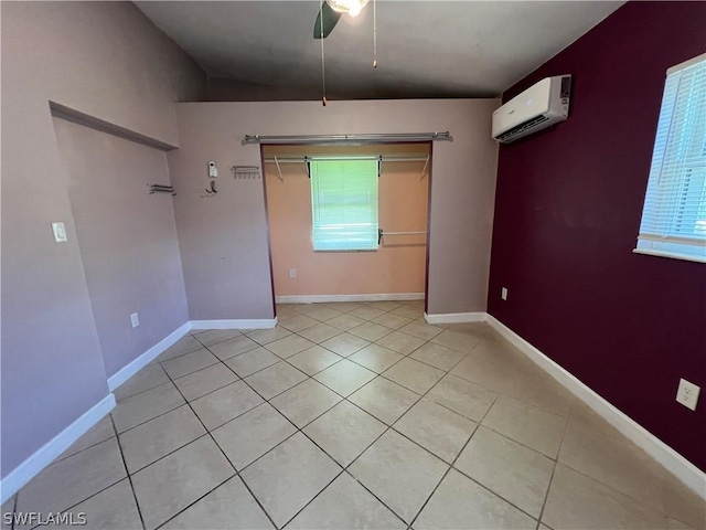 unfurnished room featuring a wall unit AC, ceiling fan, and light tile patterned floors