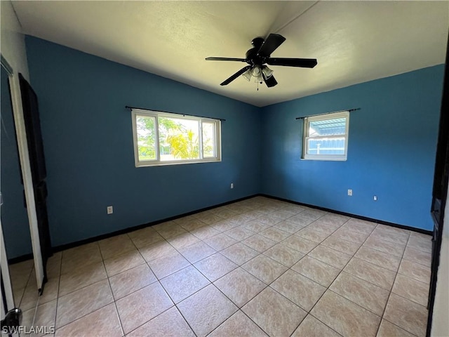 unfurnished room featuring ceiling fan, light tile patterned floors, and vaulted ceiling