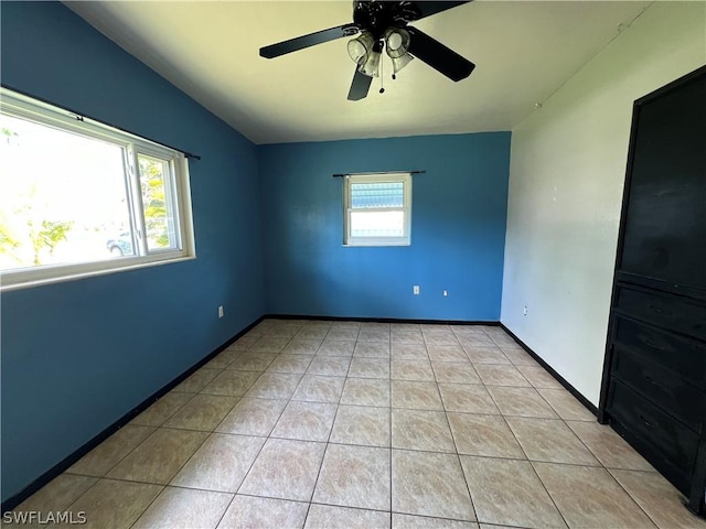 spare room featuring ceiling fan, a healthy amount of sunlight, and light tile patterned floors