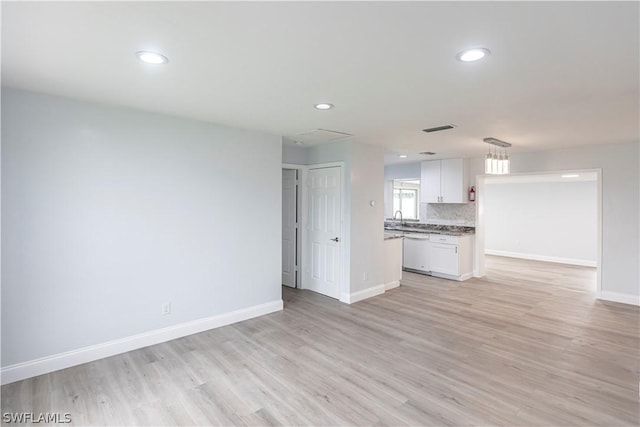 unfurnished living room featuring sink and light hardwood / wood-style floors