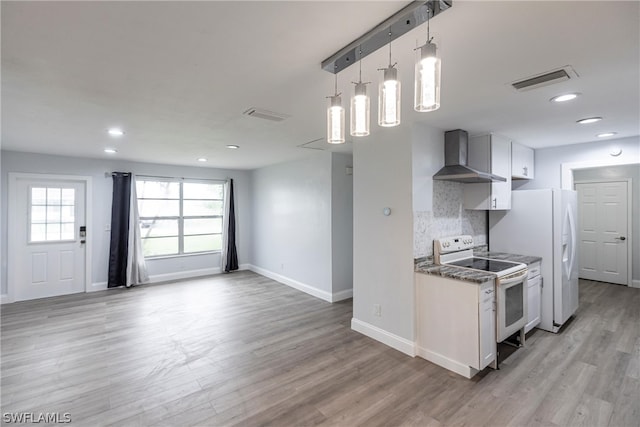 kitchen with light hardwood / wood-style flooring, tasteful backsplash, wall chimney range hood, and white appliances