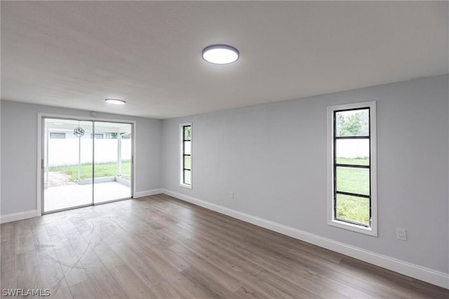 empty room with plenty of natural light and hardwood / wood-style floors