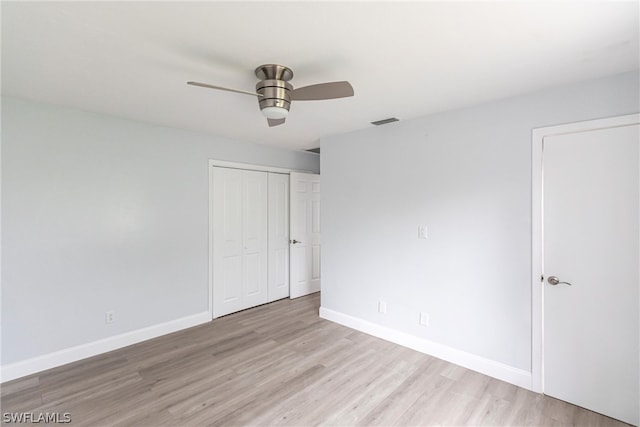 unfurnished bedroom with light wood-type flooring, ceiling fan, and a closet