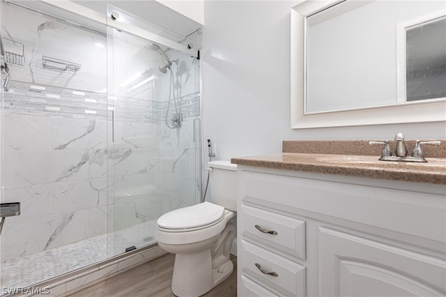 bathroom with hardwood / wood-style flooring, a shower with door, toilet, and vanity