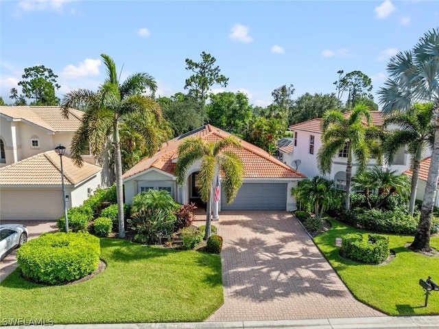 mediterranean / spanish-style home with a tile roof, decorative driveway, stucco siding, a front lawn, and a garage