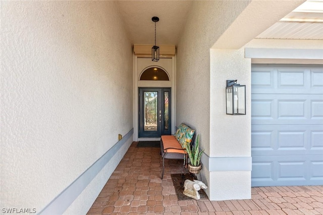 doorway to property with a garage and stucco siding