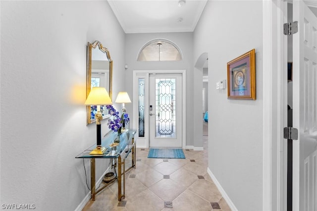 foyer entrance featuring ornamental molding, arched walkways, light tile patterned floors, and baseboards