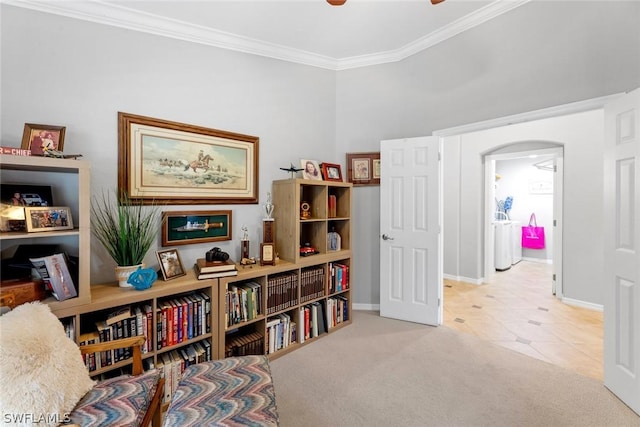 living area featuring arched walkways, ornamental molding, light carpet, baseboards, and a ceiling fan