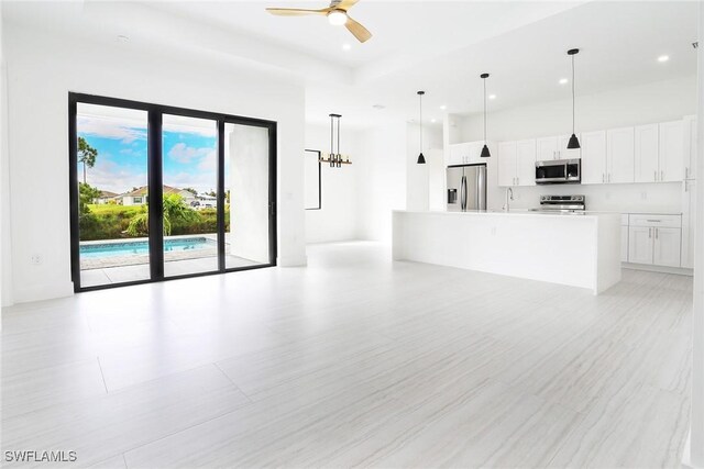 unfurnished living room with sink and ceiling fan with notable chandelier