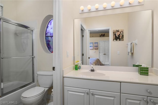 full bathroom featuring vanity, combined bath / shower with glass door, and toilet