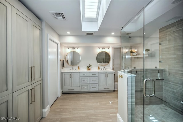 bathroom featuring an enclosed shower, a skylight, and vanity