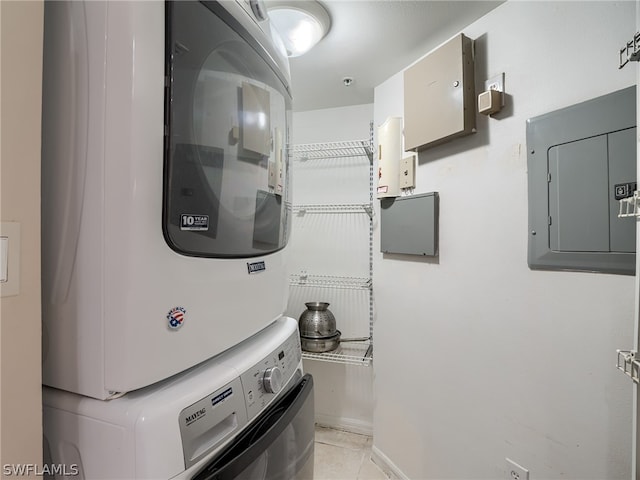 clothes washing area featuring electric panel, stacked washer and dryer, and light tile patterned flooring