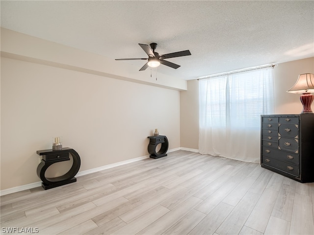 empty room with ceiling fan, light hardwood / wood-style flooring, and a textured ceiling