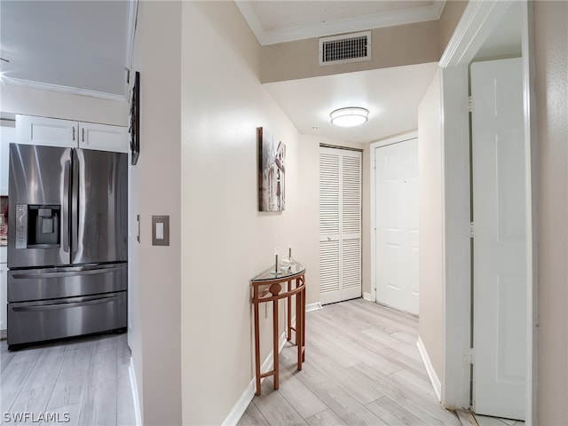 corridor with light hardwood / wood-style floors and crown molding