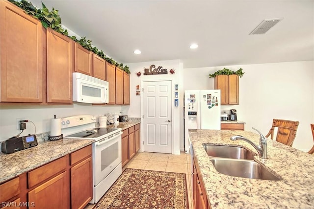 kitchen featuring light tile patterned floors, white appliances, light stone counters, and sink