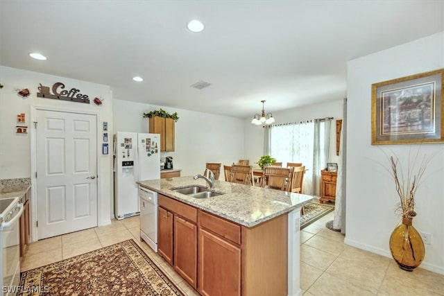 kitchen featuring sink, an inviting chandelier, an island with sink, pendant lighting, and white appliances